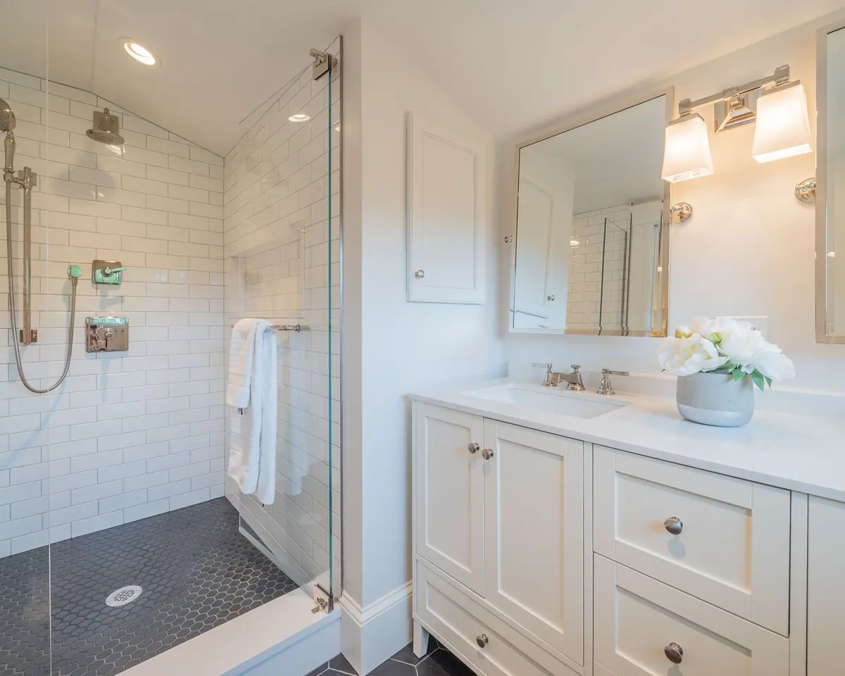 Bath with a glass-enclosed shower and a white double vanity