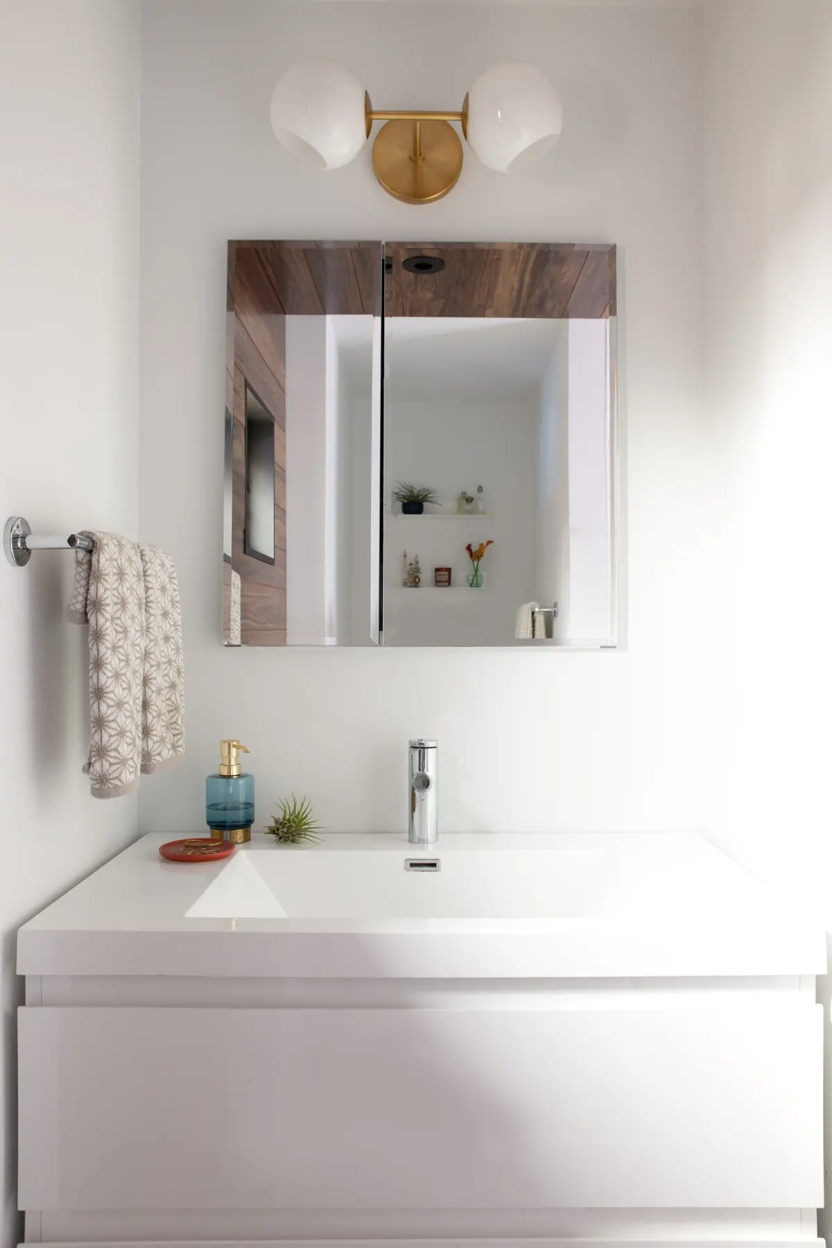 Floating white vanity under a wood-framed mirror cabinet