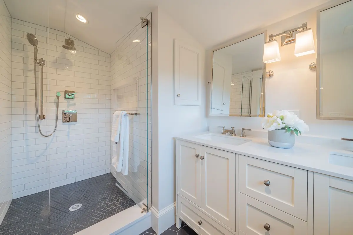 Bath with a glass-enclosed shower and a white double vanity