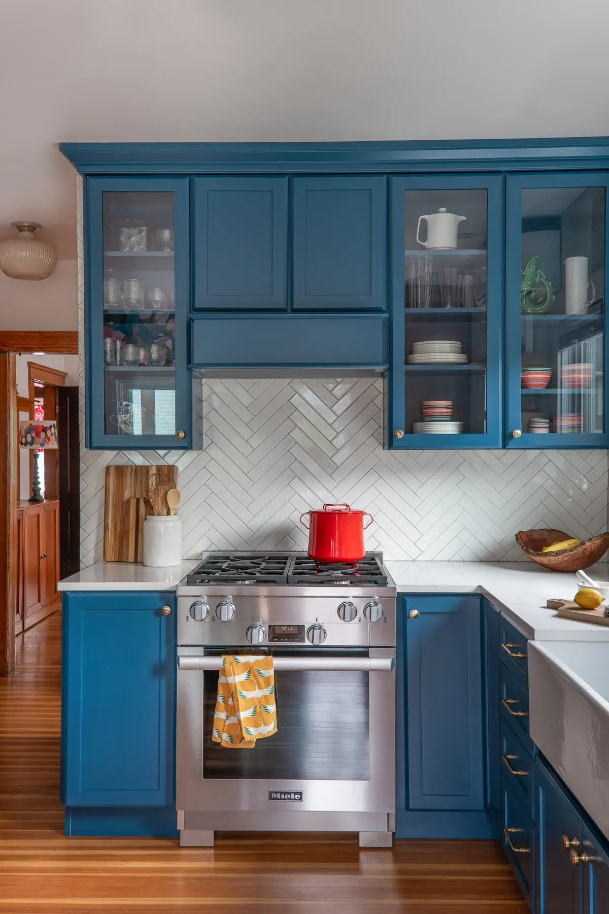 Blue kitchen cabinetry with a herringbone tile backsplash