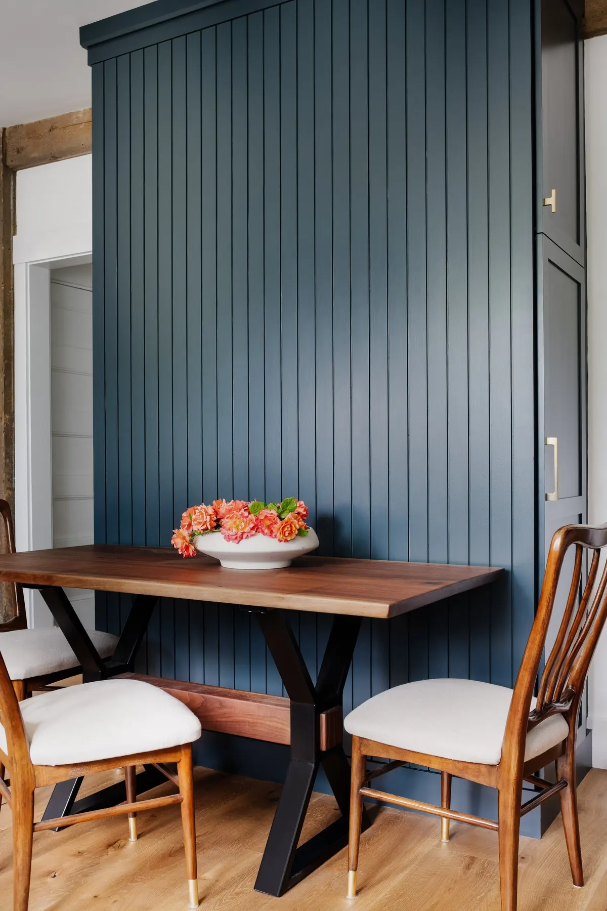 Wall paneled in deep blue beside a wood table and two chairs