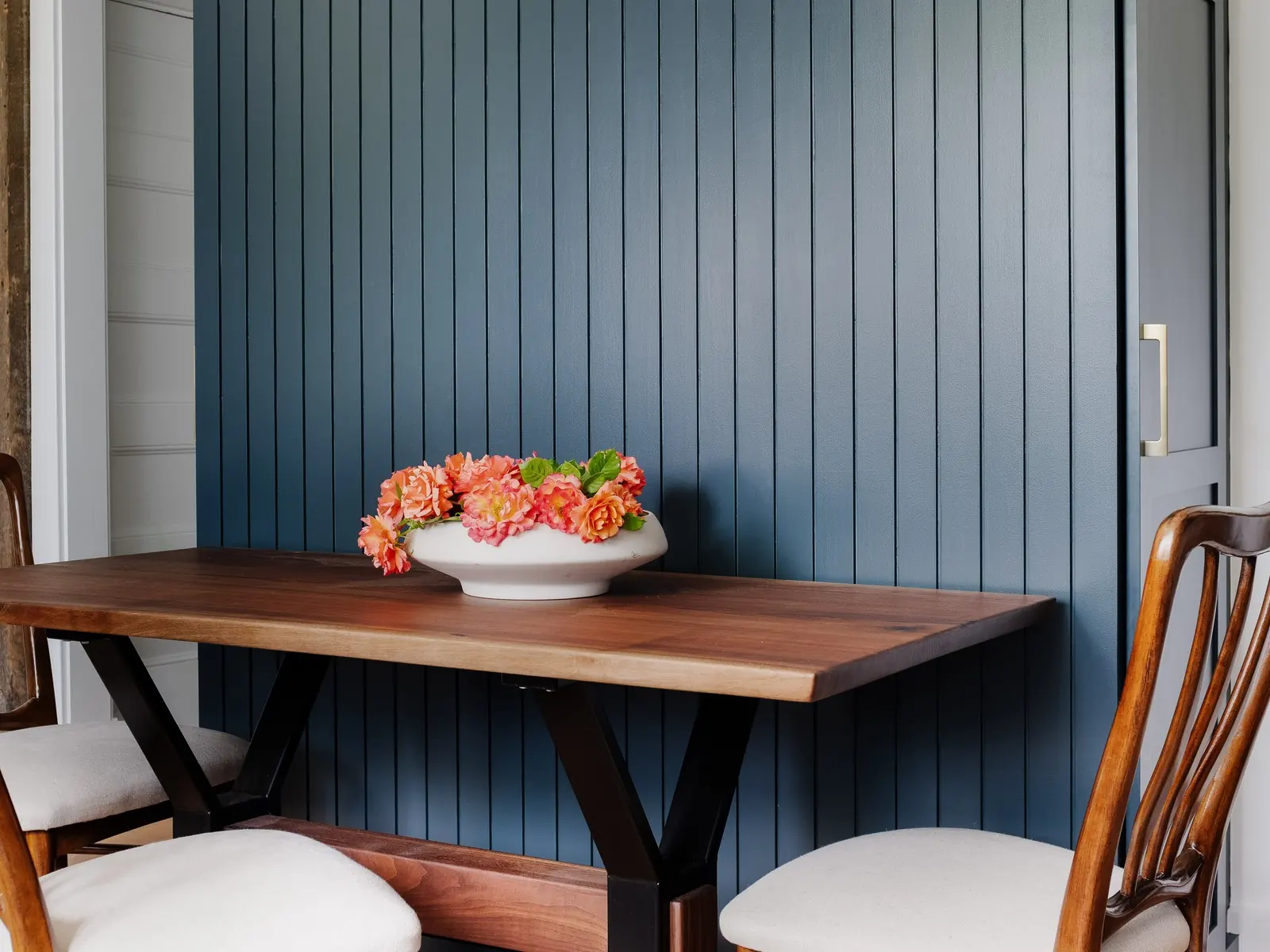 Breakfast nook with a wall paneled in deep blue, a wood table and two chairs