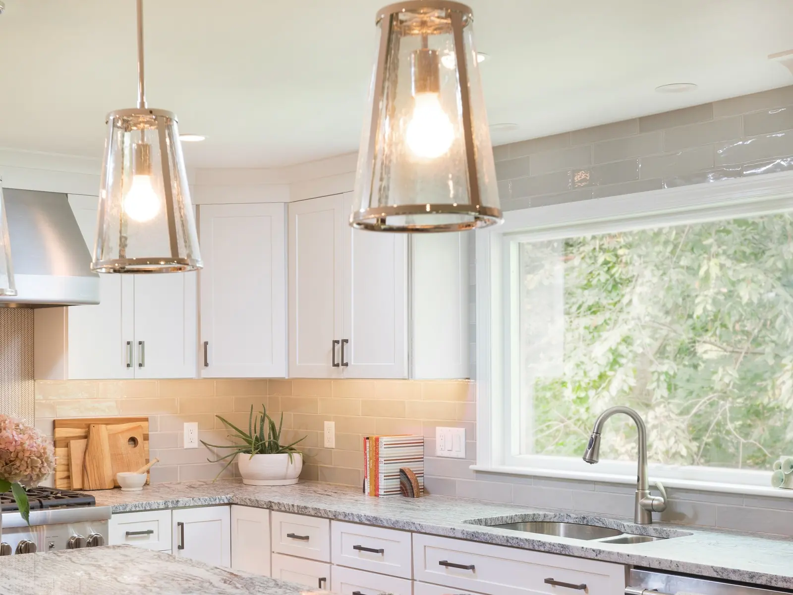 Bright kitchen with glass pendants over a stone island and a wide window