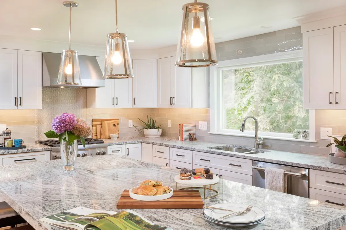 White kitchen with glass pendants over a stone-topped island