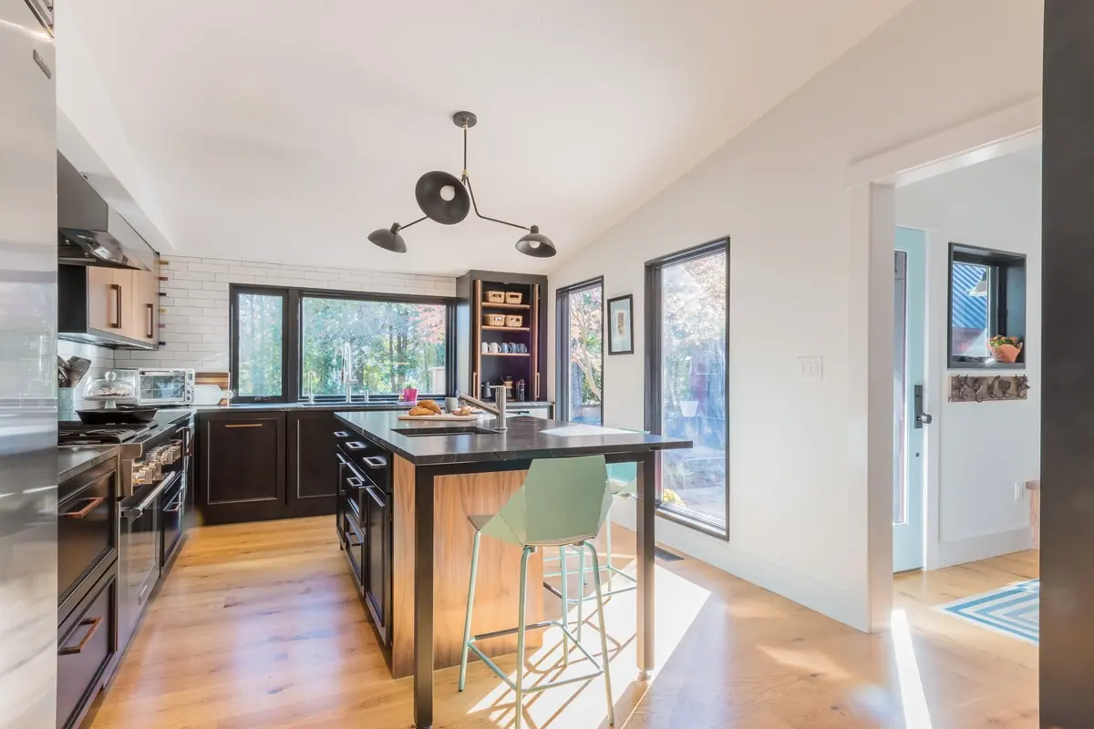 Kitchen with a wood-clad island and black-framed windows under a vaulted ceiling