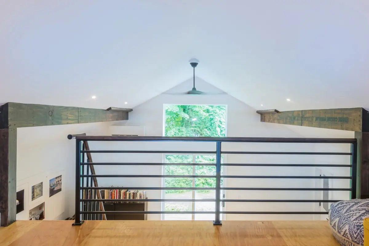 Loft landing with a black metal railing and rustic beams