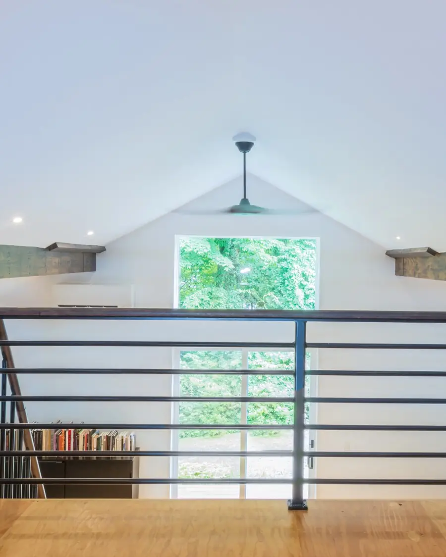 Loft landing with a black metal railing under a gable window