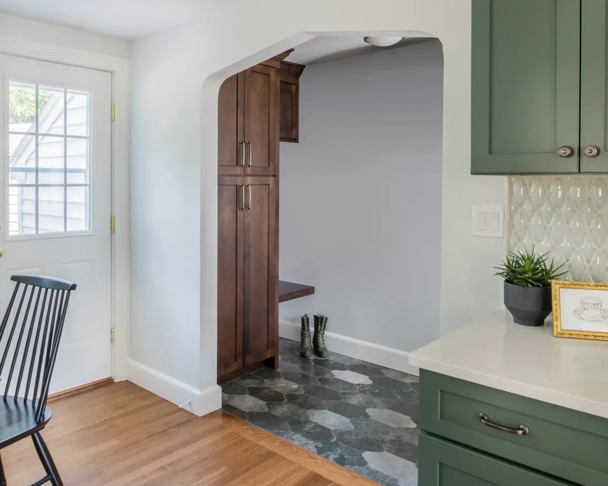 Arched opening to a mudroom with built-in wood lockers and green cabinetry