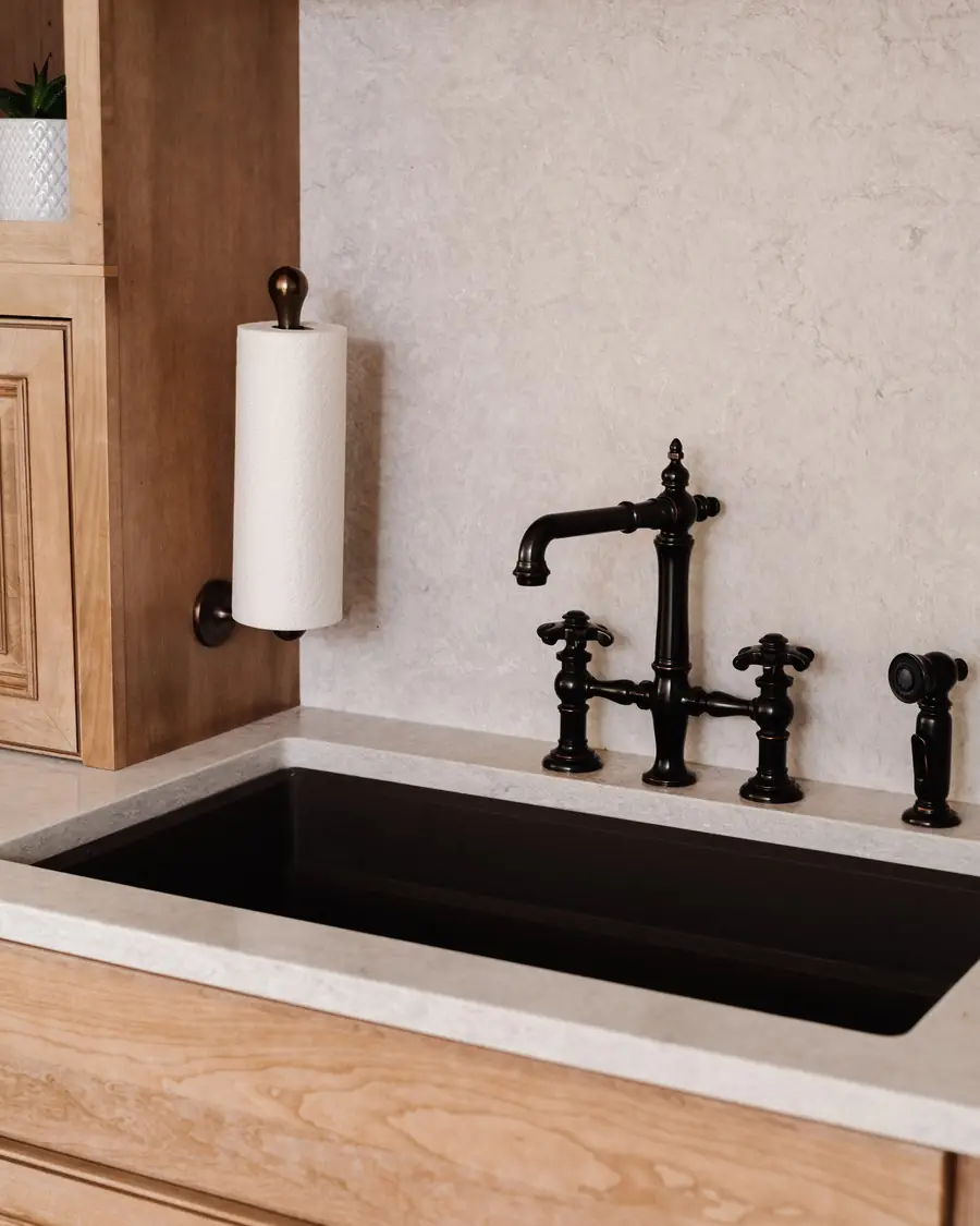 Undermount sink with a black bridge faucet set in wood cabinetry